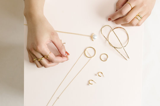 Shot of model hands with gold jewelry on pink wood block
