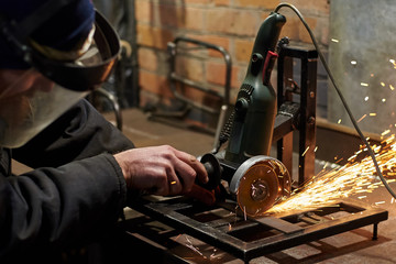A man in a protective mask cuts metal on a machine tool.