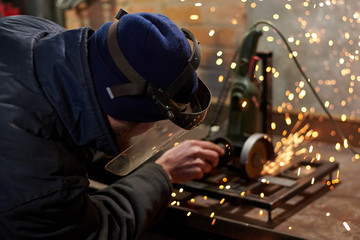 A man in a protective mask cuts metal on a machine tool.