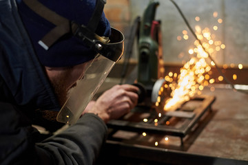 A man in a protective mask cuts metal on a machine tool.