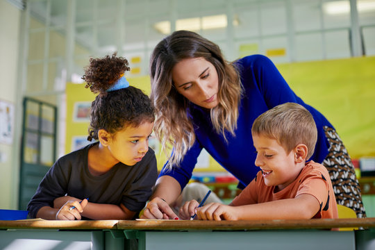 Teacher helping her young pupils in a class activity