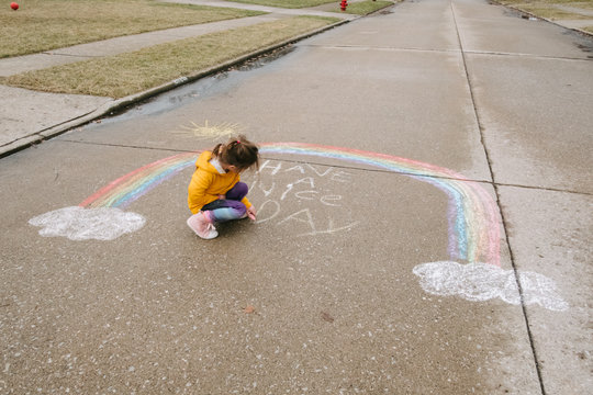 little girl writes chalk message in street