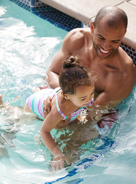 African American father teaching his daughter how to swim