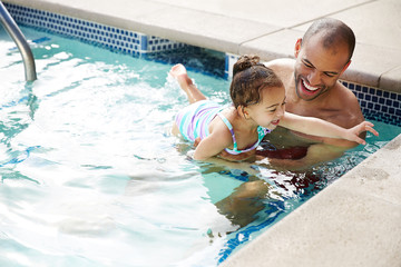 African American father teaching his daughter how to swim