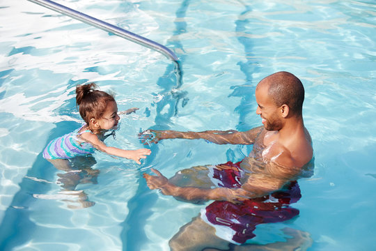 African American father giving his daughter a swim lesson - Powered by Adobe