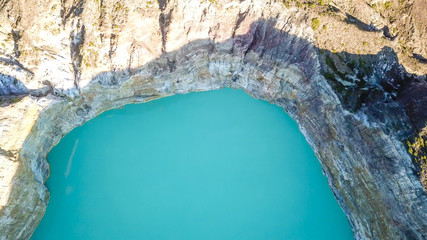 A drone top-down shot of volcano Kelimutu's crater lake in Flores, Indonesia. The lake has a very strong turquoise colour thanks to the minerals in the water. Natural phenomenon