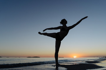 Girl Dancing Standing On Her Leg On The Seashore At Sunset.