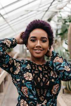 A beautiful young black woman with a purple afro in a tropical setting