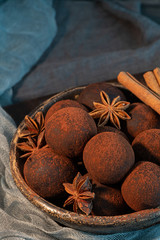 Craft chocolate truffles on plate with cocoa powder and anise, cinnamon, cardamom.