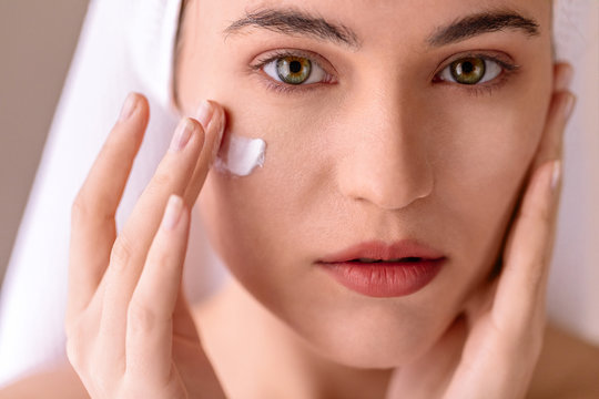 Young woman putting face cream