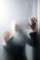 Person trapped behind cracked glass with bullet hole