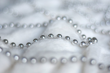 Line of silver beads garland thread chain on a white soft blanket