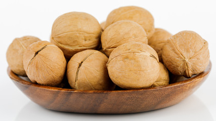 Whole walnut in a wooden bowl. On white background