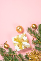 Golden Christmas flat lay background on pink with present box and decorations.