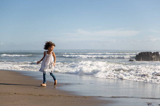Cute girl running away from the waves