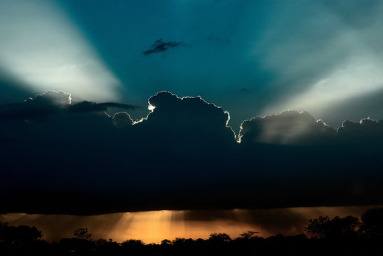 Glowing sun behind dark overcast in sunset