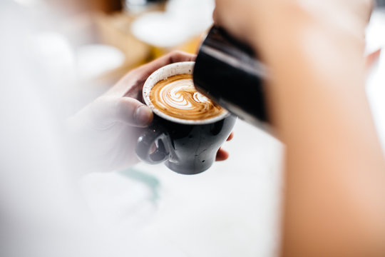Hand pouring coffee with latte art