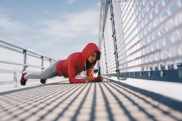 A woman doing planks in an urban outdoor area.