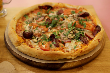 pizza with mushrooms, ham, vegetables and herbs on the table in the pizzeria