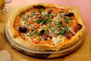 pizza with mushrooms, ham, vegetables and herbs on the table in the pizzeria