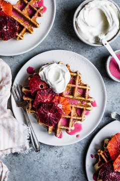Fluffy and crispy chamomile waffles made gluten-free with oat, sweet rice, and tapioca flours. Drizzled with hot pink blood orange glaze and topped with festive orange supremes and whipped cream
