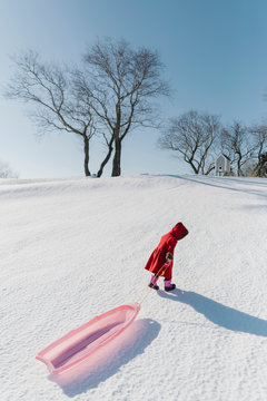 Child In Red Coat Trudging up to Sledding Hill