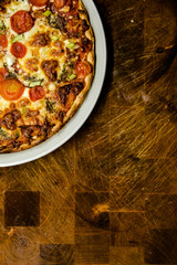 Homemade pizza with cherry tomatoes on dish on dark wooden table.