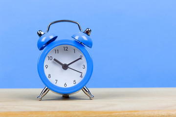 blue alarm clock on the table, blue background, copy spaсe	