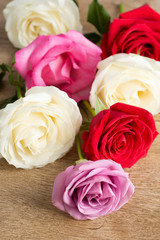 Group of white, red and pink roses over a wooden table