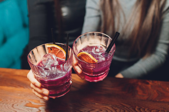 Woman's Hand Holding Old Fashioned Glass With Cold Cocktail Against Blurred Night Club Background.