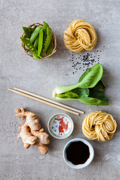 Snow peas, egg noodles, bok choy, ginger root, sesame seeds, soy sauce and chopsticks