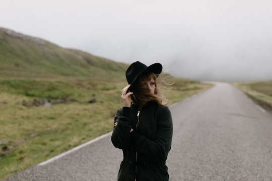 Girl walking in the middle of the road in the north atlantic with fog behind her