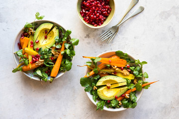Healthy salad bowl with roast carrots, watercress greens, pomegranate and avocado