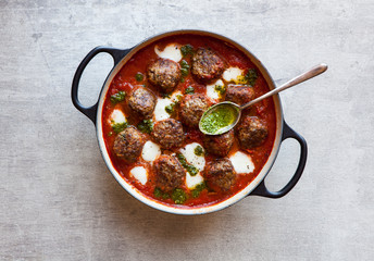 Baked meatballs with tomato, melted mozzarella cheese and herb pesto sauce