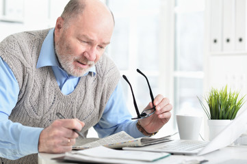 Portrait of emotional senior man reading newspaper at home