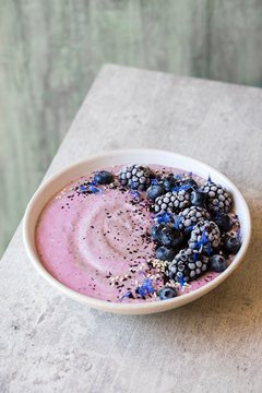 Breakfast smoothie topped with berries, acai berry powder, toasted sesame seeds