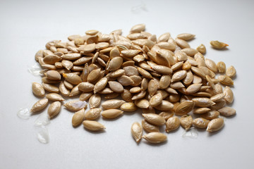 Unpeeled ripe fresh fragrant tasty light brown pumpkin seeds on a white background