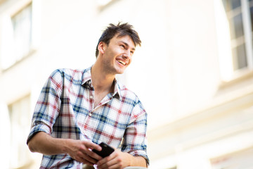 handsome young guy sitting outside holding mobile phone in hand