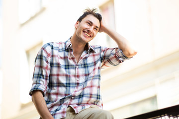 handsome young guy smiling with hand in hair outside