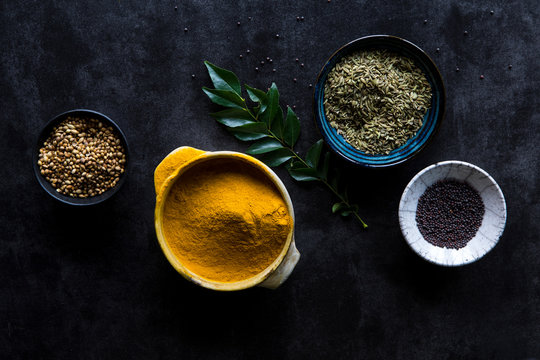 Cooking spices in bowls with curry leaf