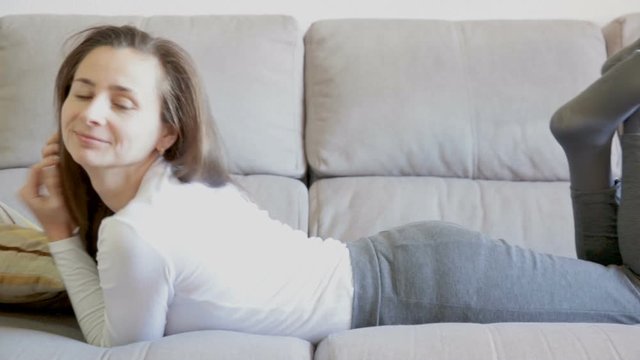 Portrait of young woman lying and relaxing on sofa at home