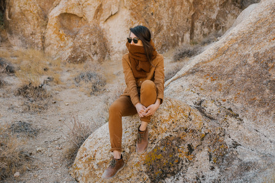 Young woman sitting alone on a rock in the desert