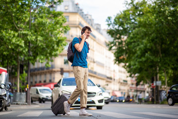 Full body young travel man walking and talking on city street with cellphone