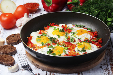 Shakshouka with five cooked eggs on top of tomato sauce in cast iron skillet