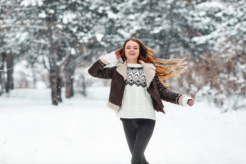 Fototapeta na wymiar Happy young woman engoing winter, frosty day. Playing with snow on winter holidays. Woman Walk in winter forest.