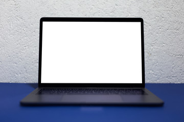 Close-up of modern laptop with empty mockup, on phantom blue desk, background of white textured wall.