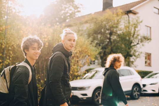 Portrait of smiling friends walking together in city during autumn