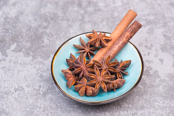 star anise and cinnamon in a bowl on a grey structured background