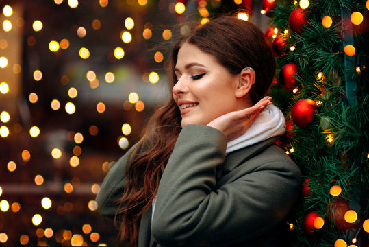 A Girl With A Hearing Aid. The Girl Assumes Hearing Aid.Happy Girl That Hears Well Again. Holiday Concept. Decorating Christmas Tree. Beautiful  Woman On Christmas Background.