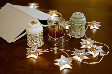 Una taza de té, rodeada de unas latas de decoración y luces en forma de estrellas